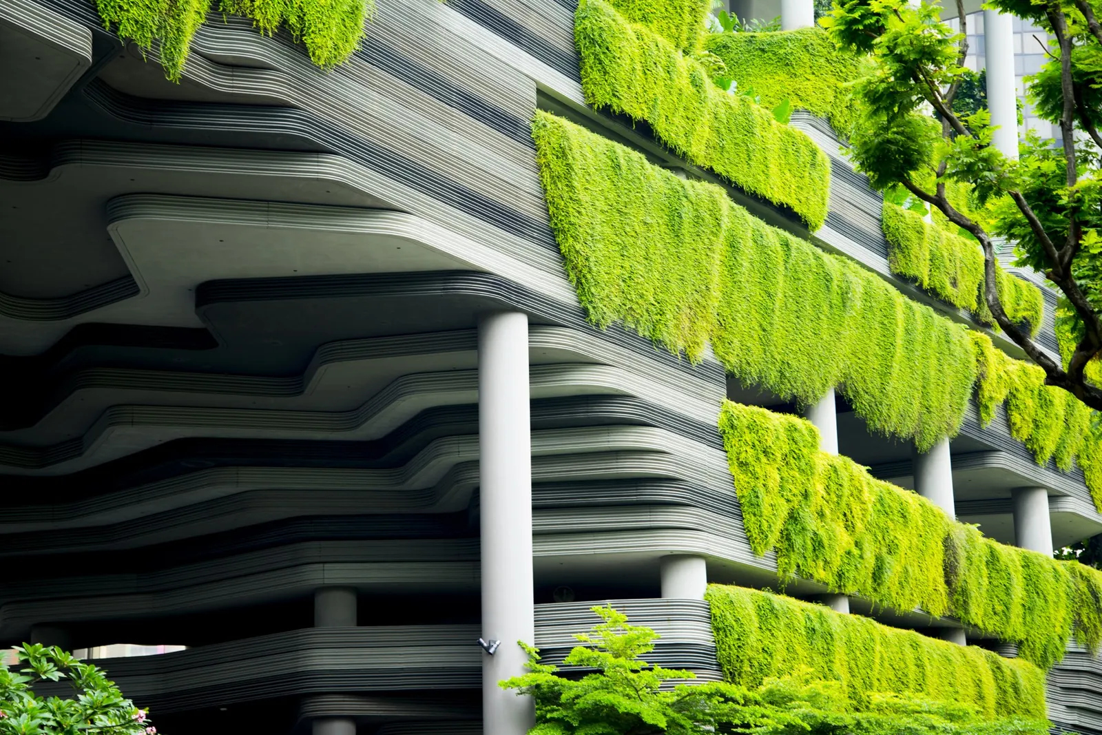 Fachada de un edificio de hormigón con jardines verticales en cada planta
