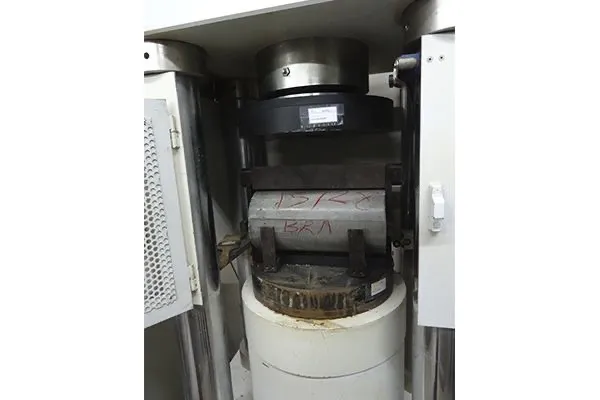 Probeta cilíndrica de hormigón colocada en la prensa de rotura a compresión